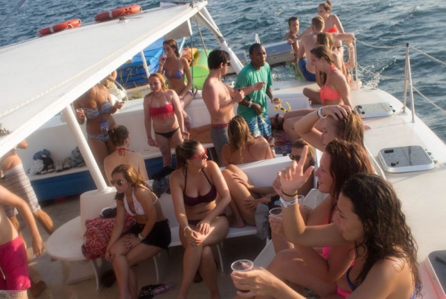 varias chicos sentadas en un barco y otros de pie